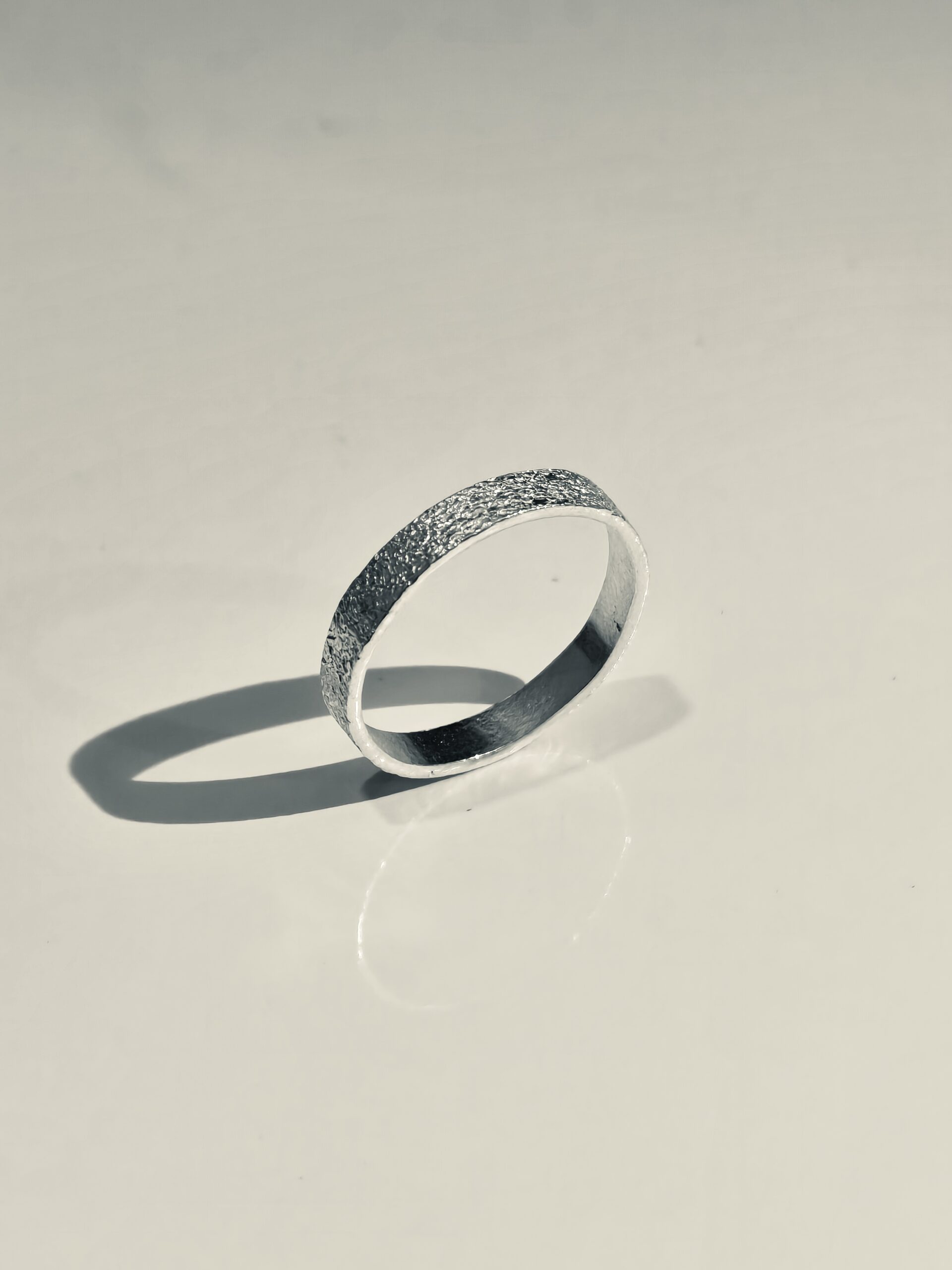 Textured 999 fine silver band standing on a neutral surface